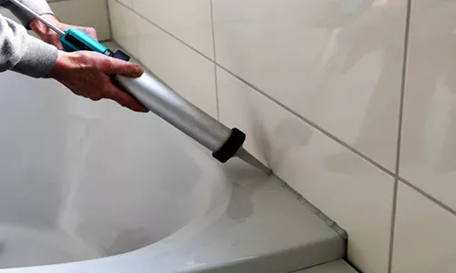 Man sealing a bath or basin with silicone