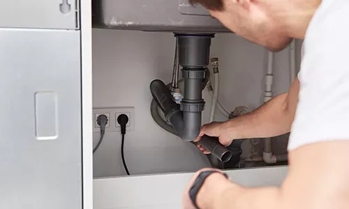 Male plumber repair sink pipe in the kitchen